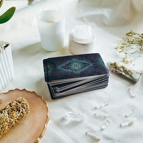 A tarot reading table with tarot cards, crystals, candles, plants and mini flowers